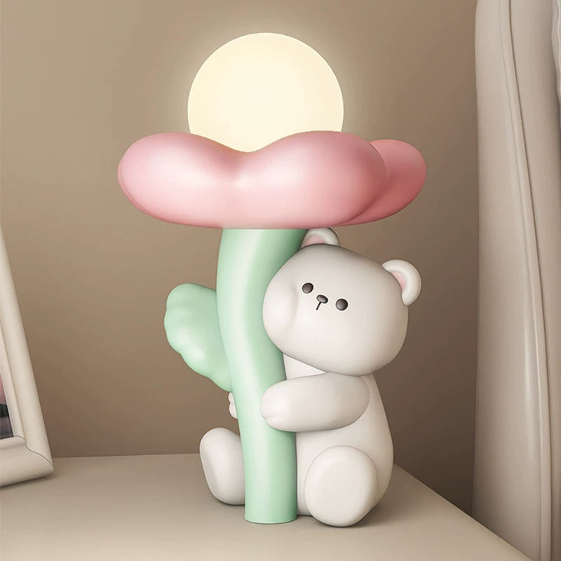 Lâmpada de Mesa Mimosa modelo urso com flor rosa, plano próximo em mesa, estrutura em resina com LED integrado e porta USB, iluminação confortável para área de trabalho e criado-mudo de quarto