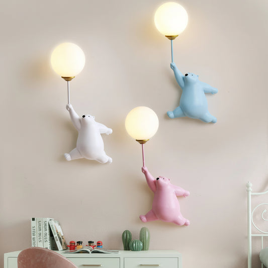 Arandela Infantil Mimosa Urso e Balão nas cores branca, rosa e azul claro, com efeito de luz quente LED tricromática, exibida em ambiente de quarto de criança decorado